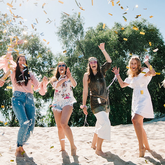 Beautiful happy stylish sexy young girls stand in beach and opens colored confetti on background nature. Party  Style boho. Maiden evening Hen-parties. Bachelorette. Close up. Portrait. Place for text